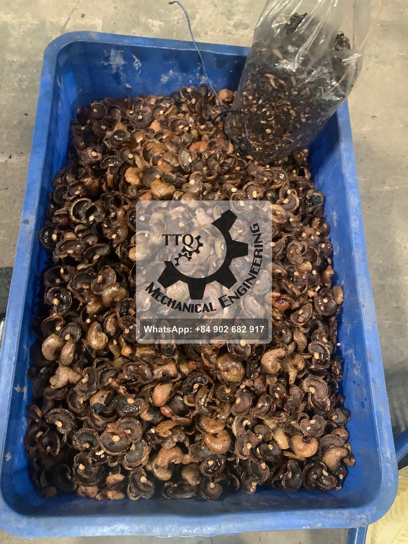 A crate of empty cashew shells after shelling, with a bag of shell fragments alongside