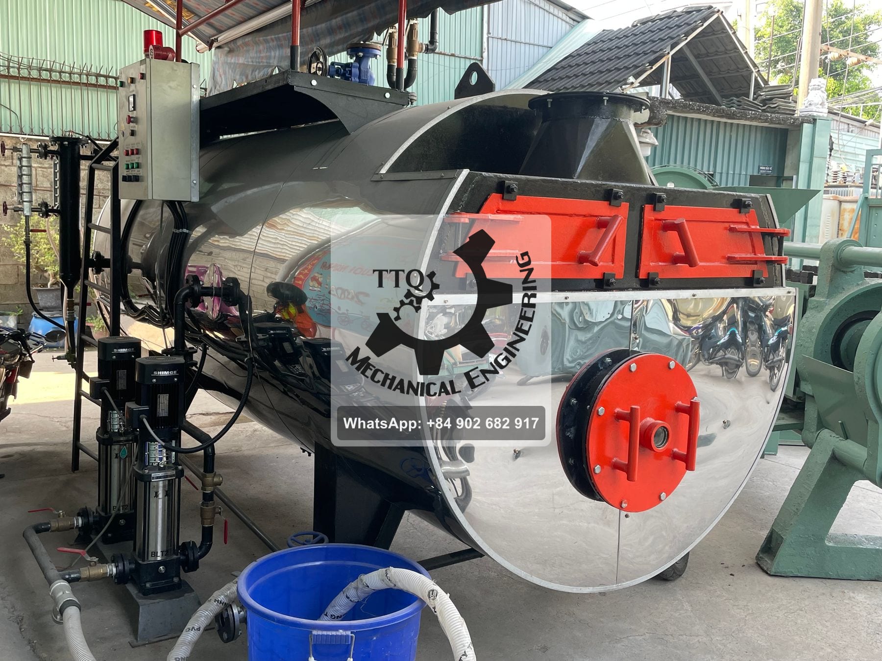 A horizontal fire-tube steam boiler at the end of build, with fire and ash doors, water column and twin feed pumps